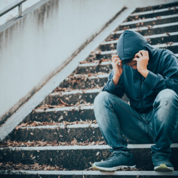 Stressed teen sitting on stairway; facing consequence of drug abuse as a teen.