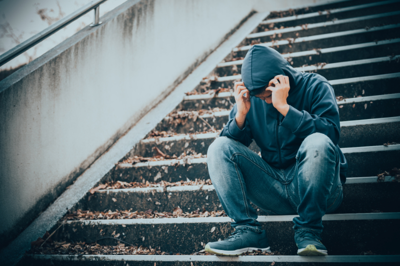 Stressed teen sitting on stairway; facing consequence of drug abuse as a teen.