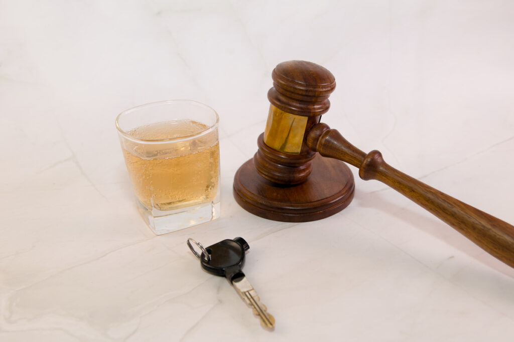 Legal gavel placed beside a drink and car keys, symbolizing the dangers of drinking and driving at court.
