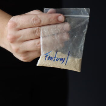 Woman holding a pack with fentanyl powder to illustrate the drug addiction